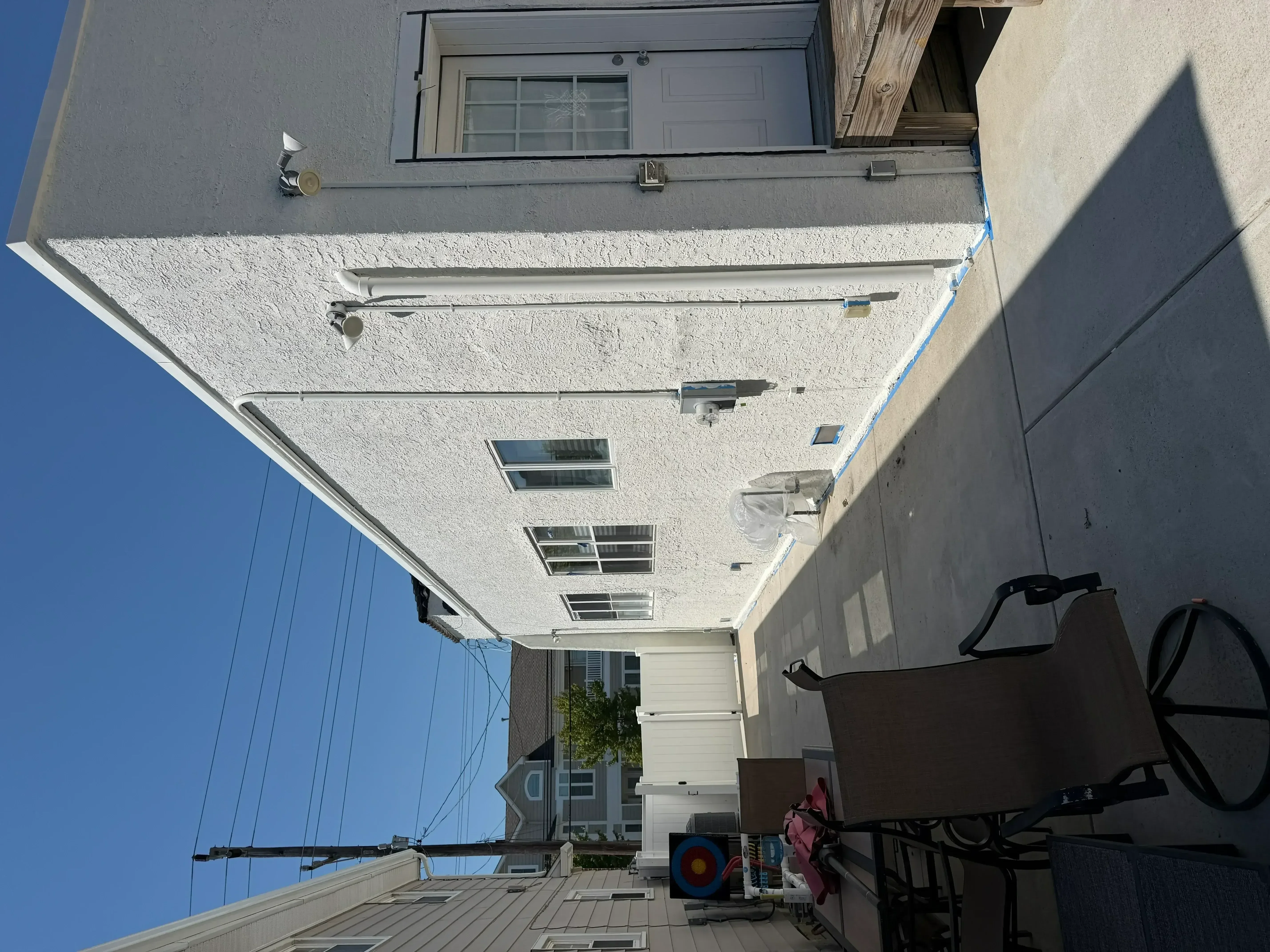 White stucco exterior wall with painted aluminum gutters, fascia, and window trim