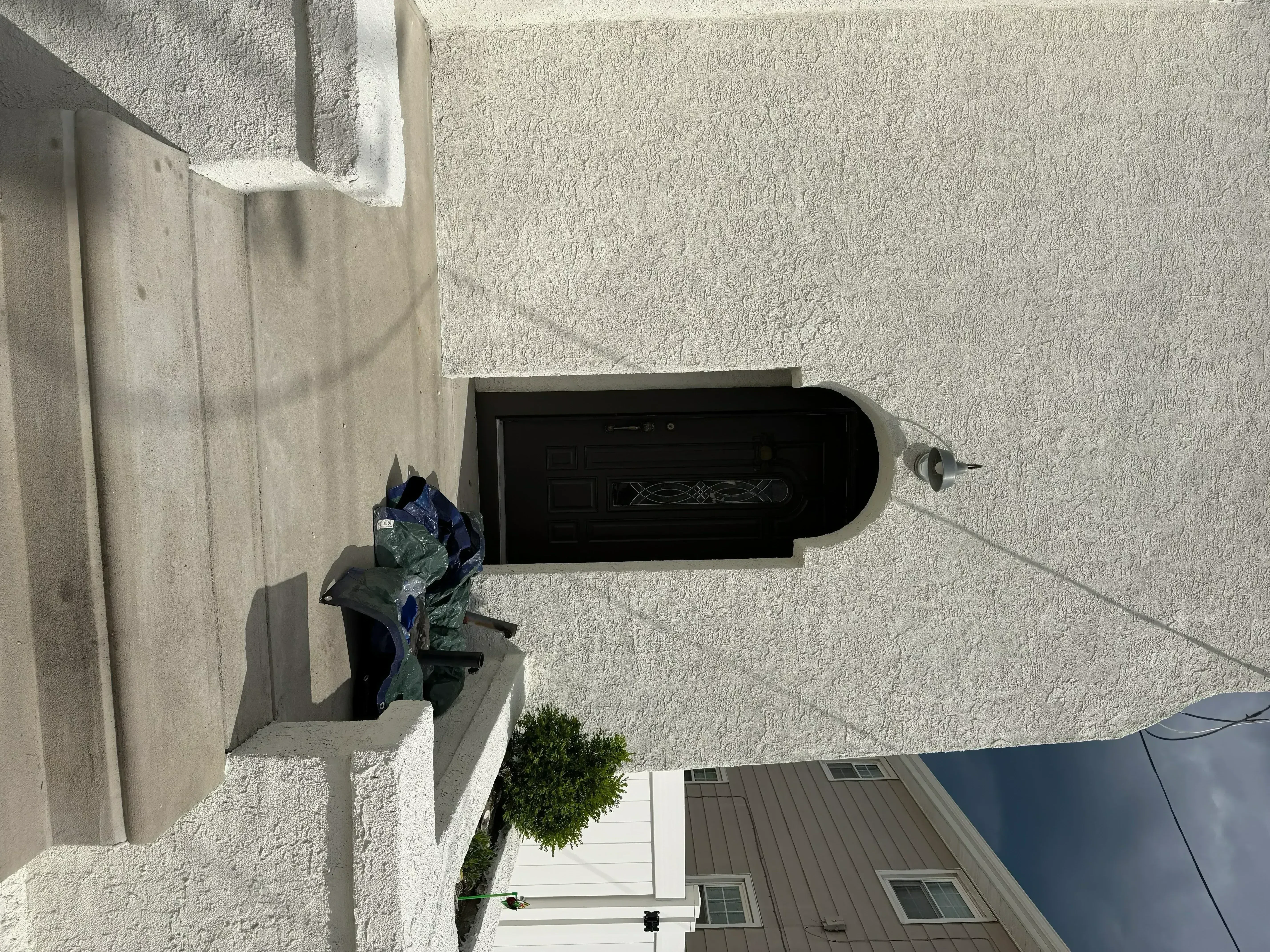 Bright white painted stucco exterior wall with textured finish and black entry door