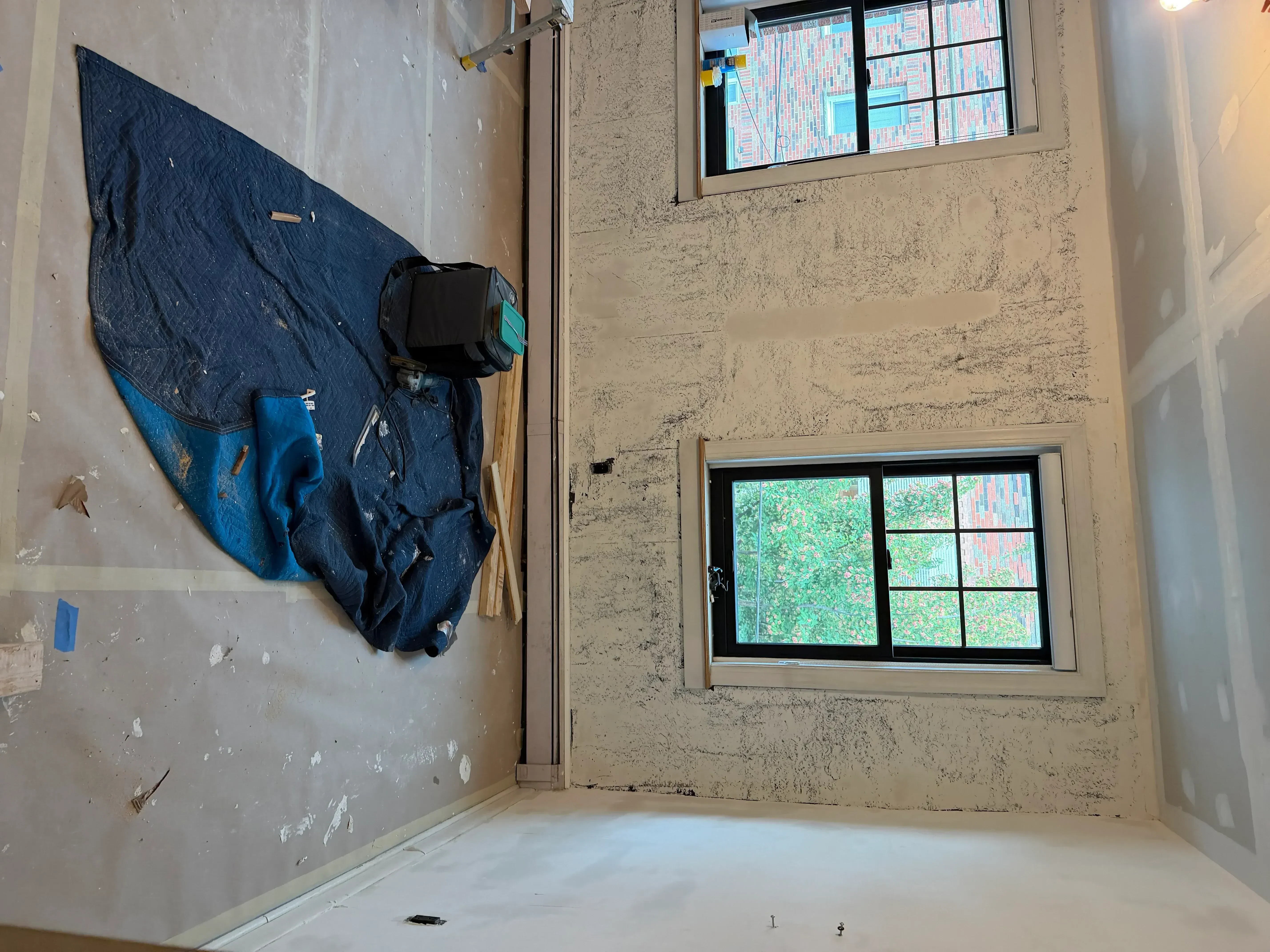 Drywall repair and finishing work with installed windows and protective coverings in residential interior