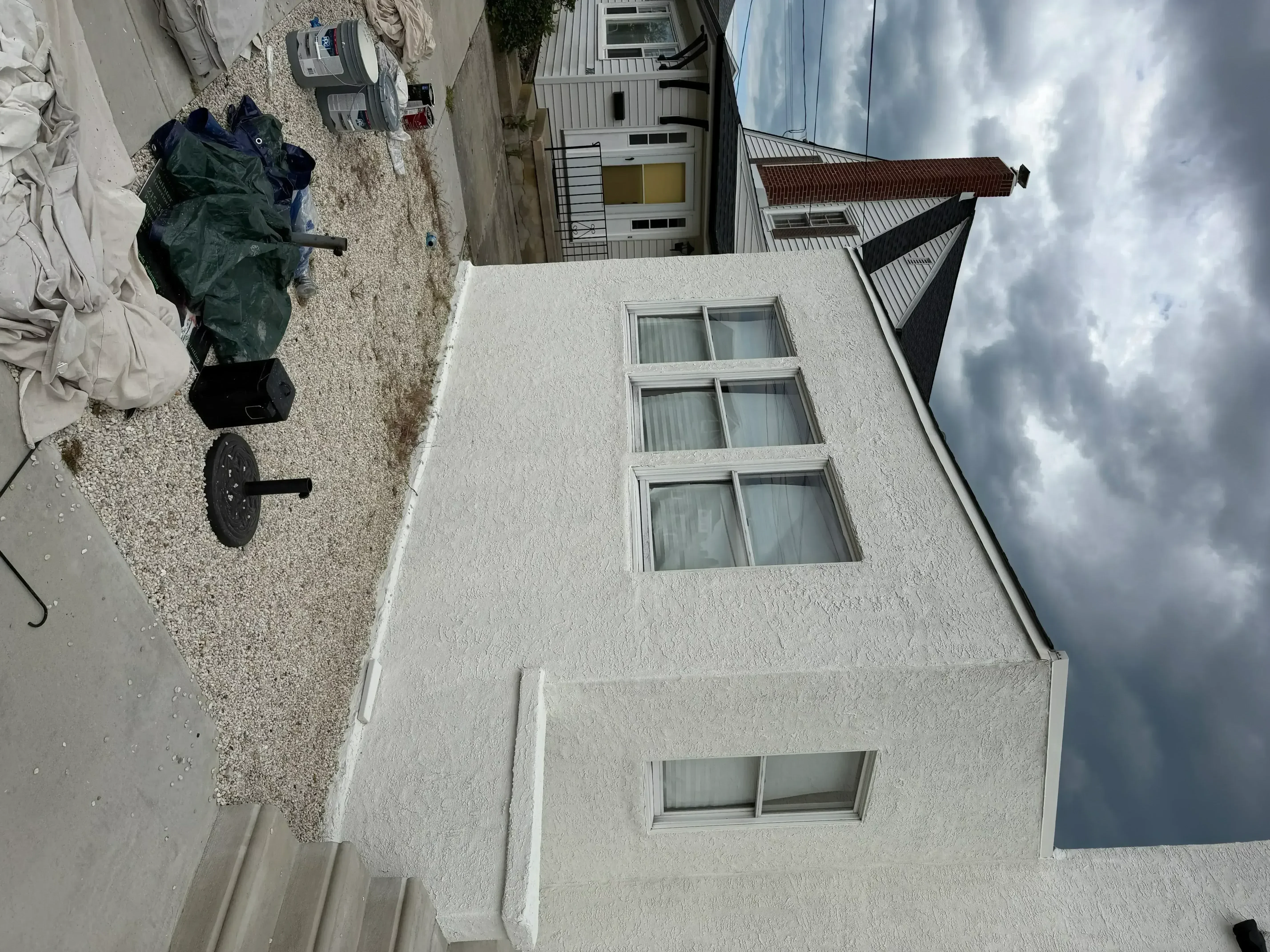 White stucco exterior wall with windows, freshly painted residential building facade