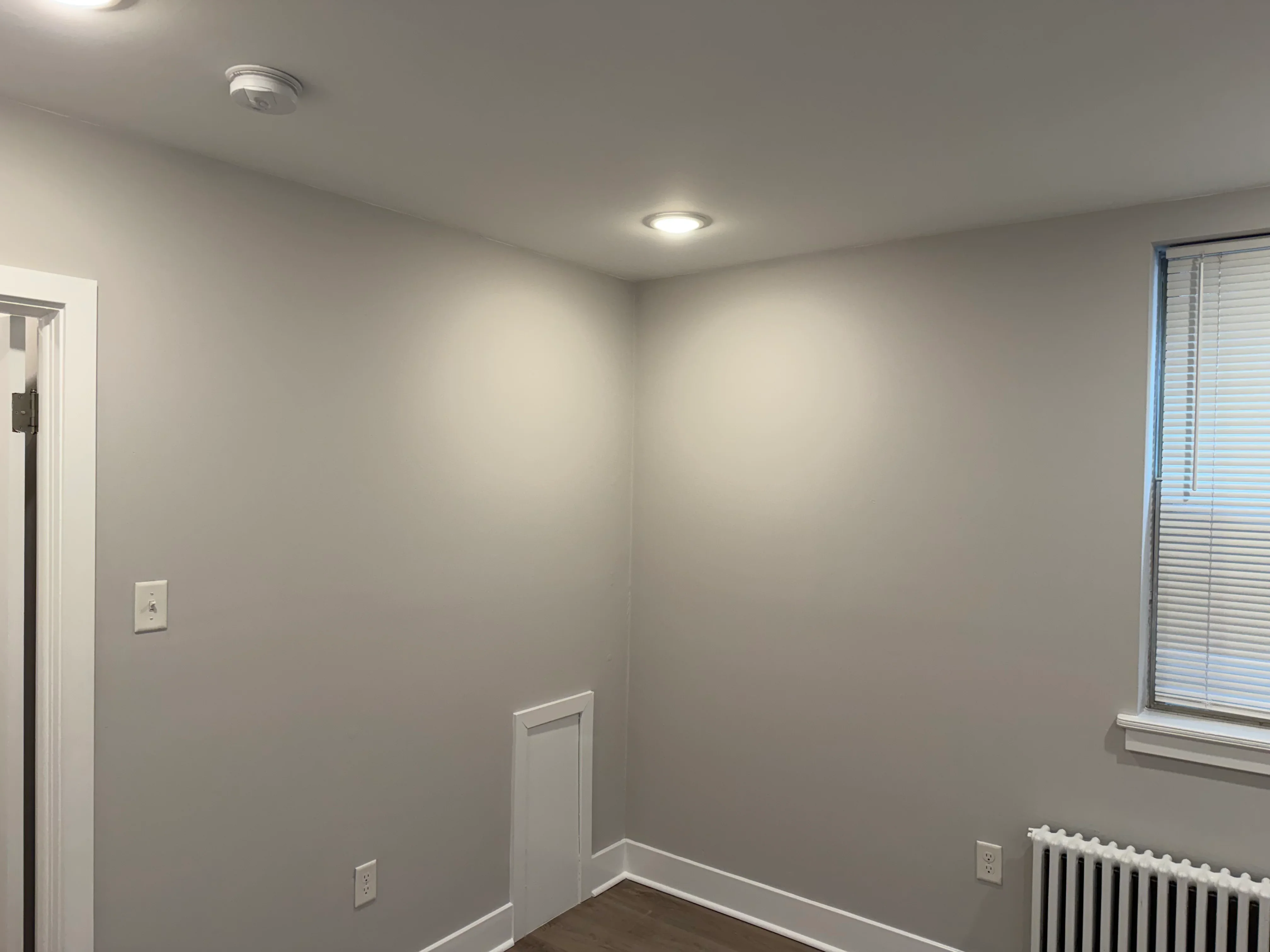 Gray painted walls with white trim, recessed lighting, and painted electrical outlets in finished interior room
