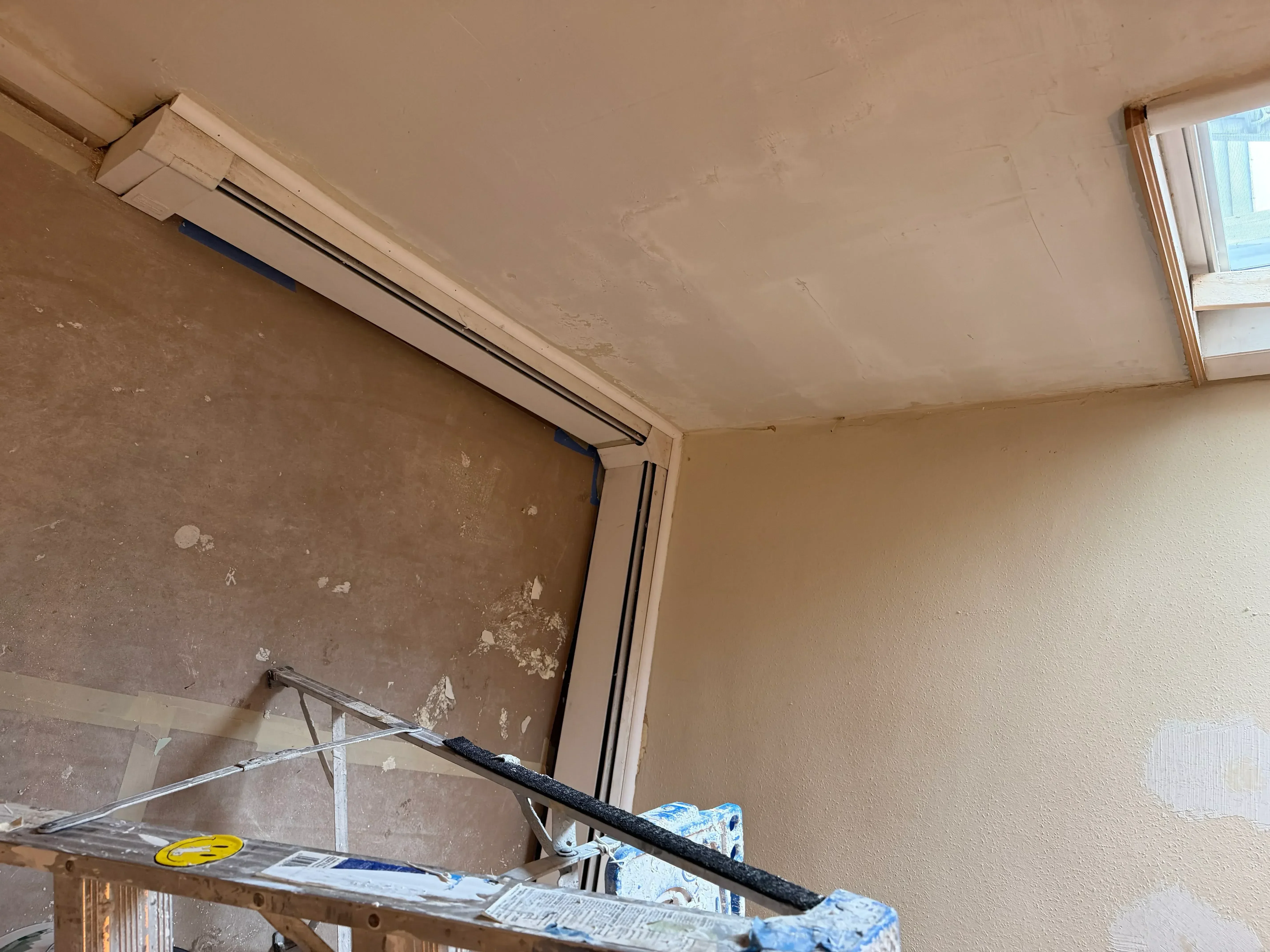 Drywall sheets with joint compound taping and protective paper coverings on walls and ceiling