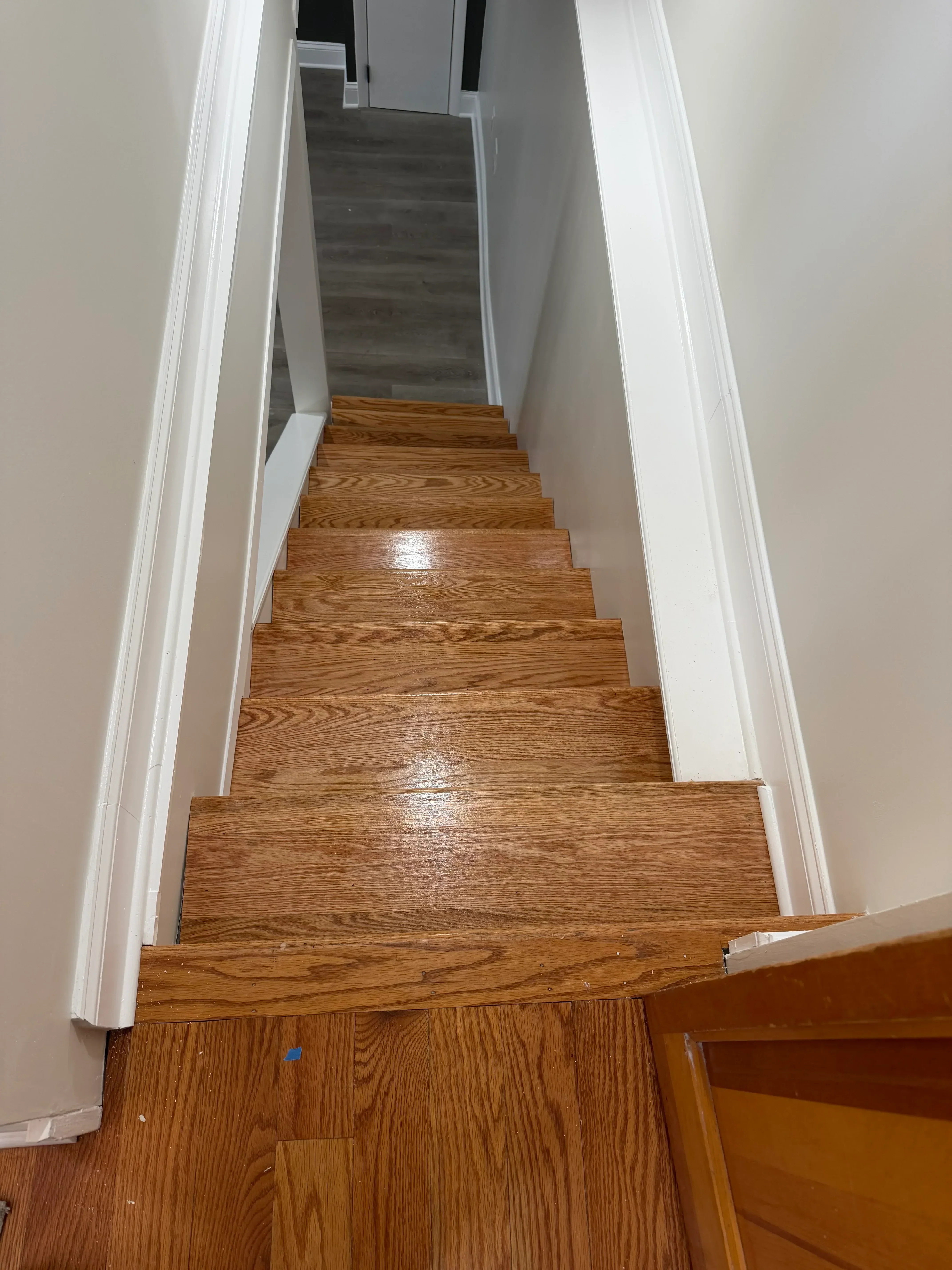 White painted trim and crown molding on interior staircase with oak wood railings and treads