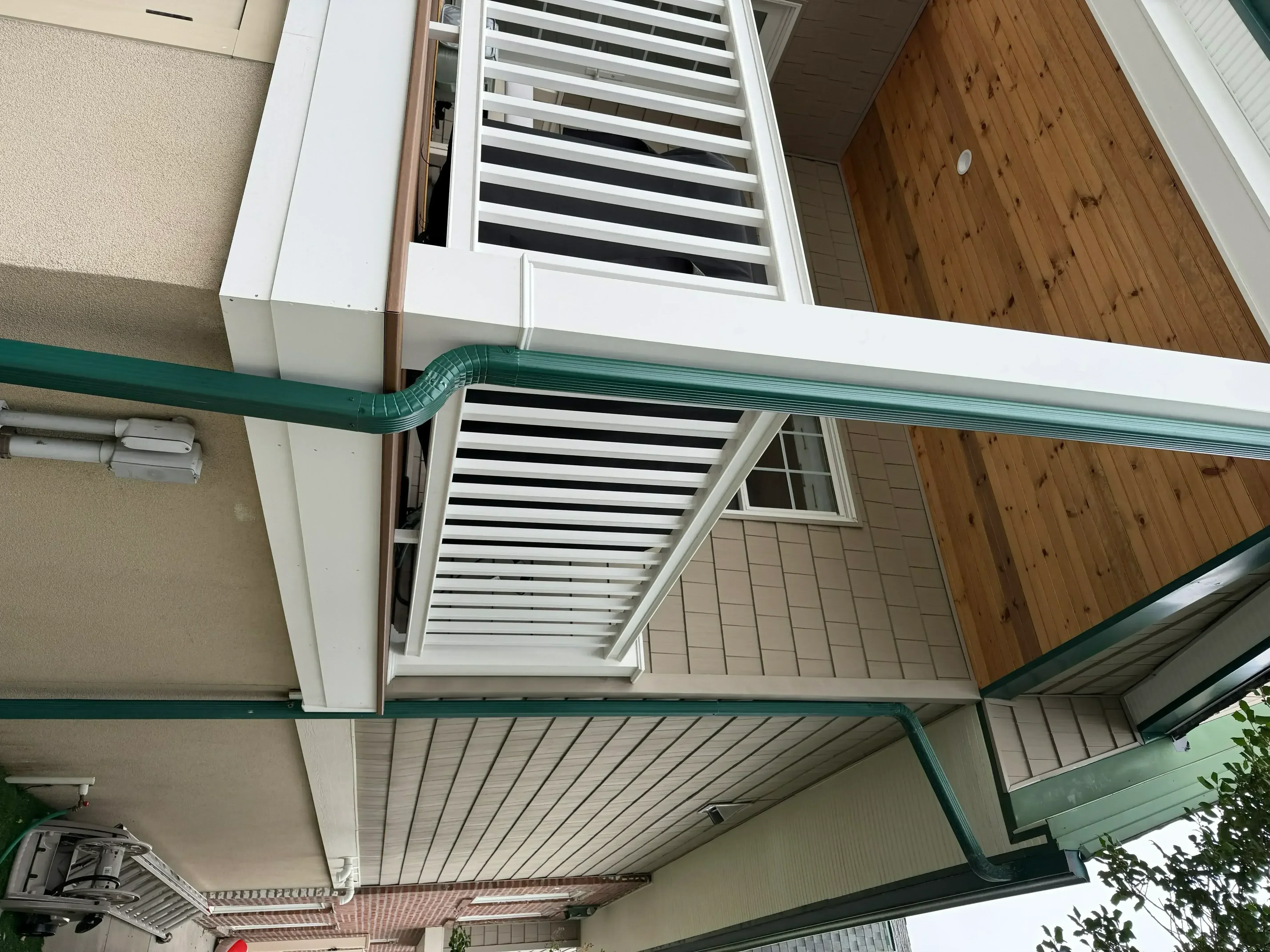Gray composite deck with white trim railings and green accent trim on residential exterior