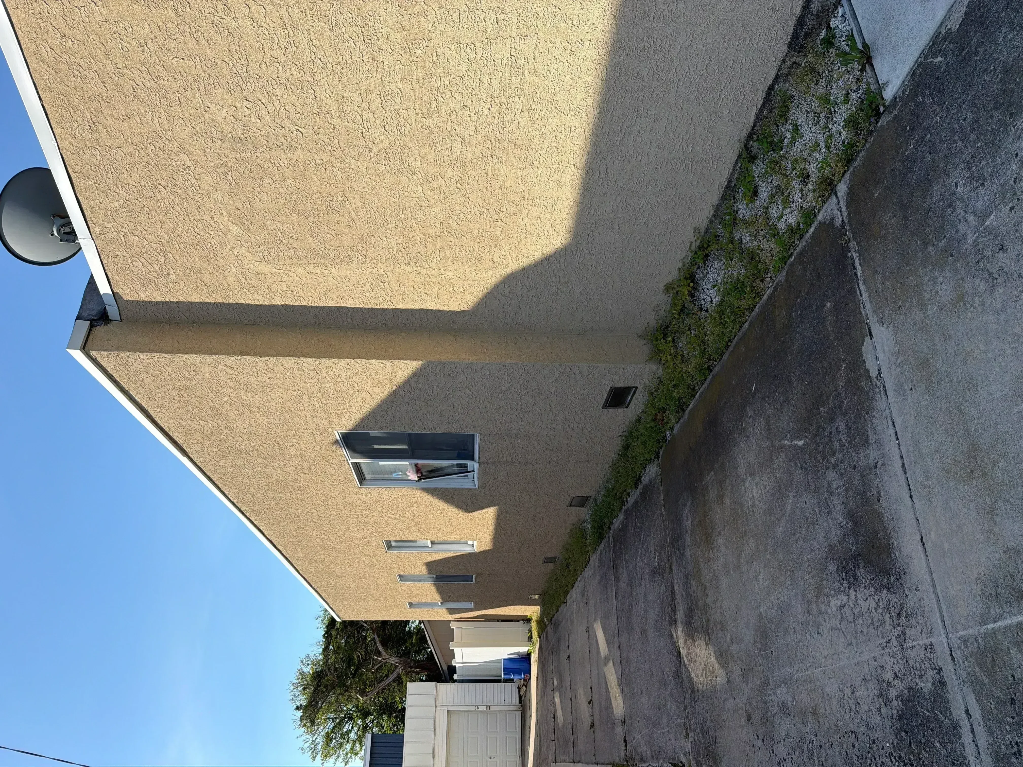 Freshly painted tan stucco exterior wall with windows and white trim