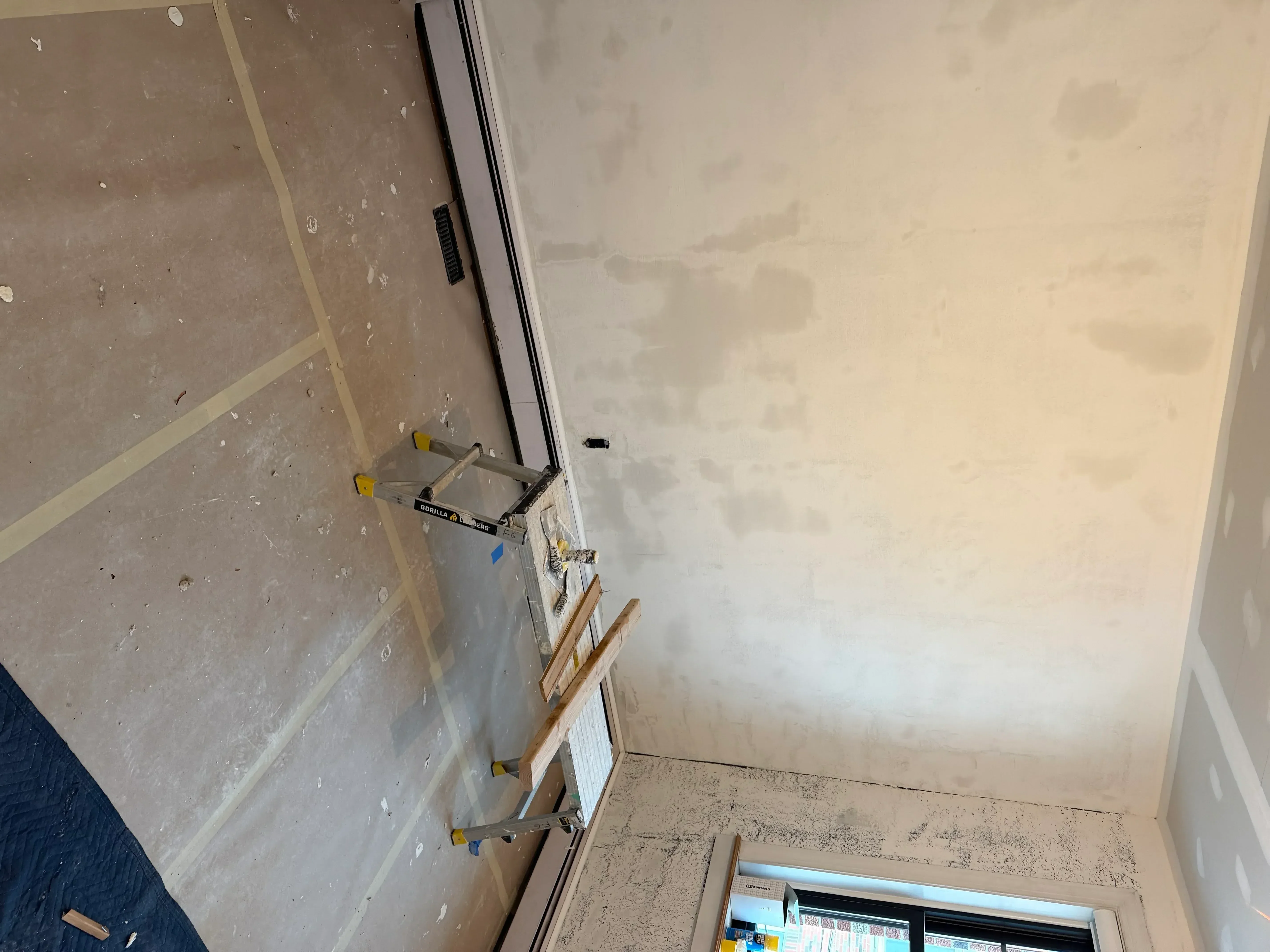 Drywall with taped seams, joint compound, and primer coating in interior room
