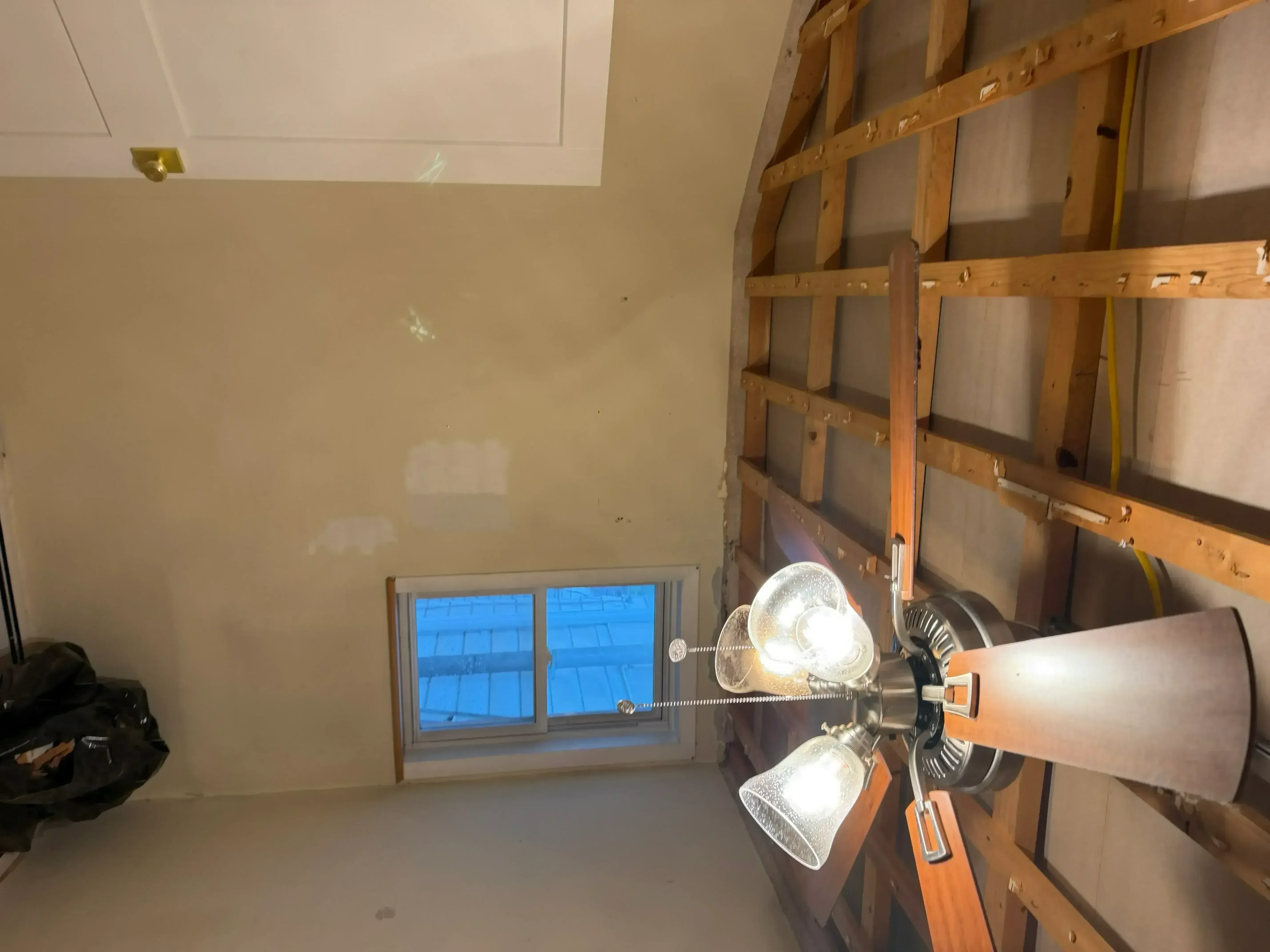 Basement interior with drywall taping, primer coat, and work lights during painting preparation
