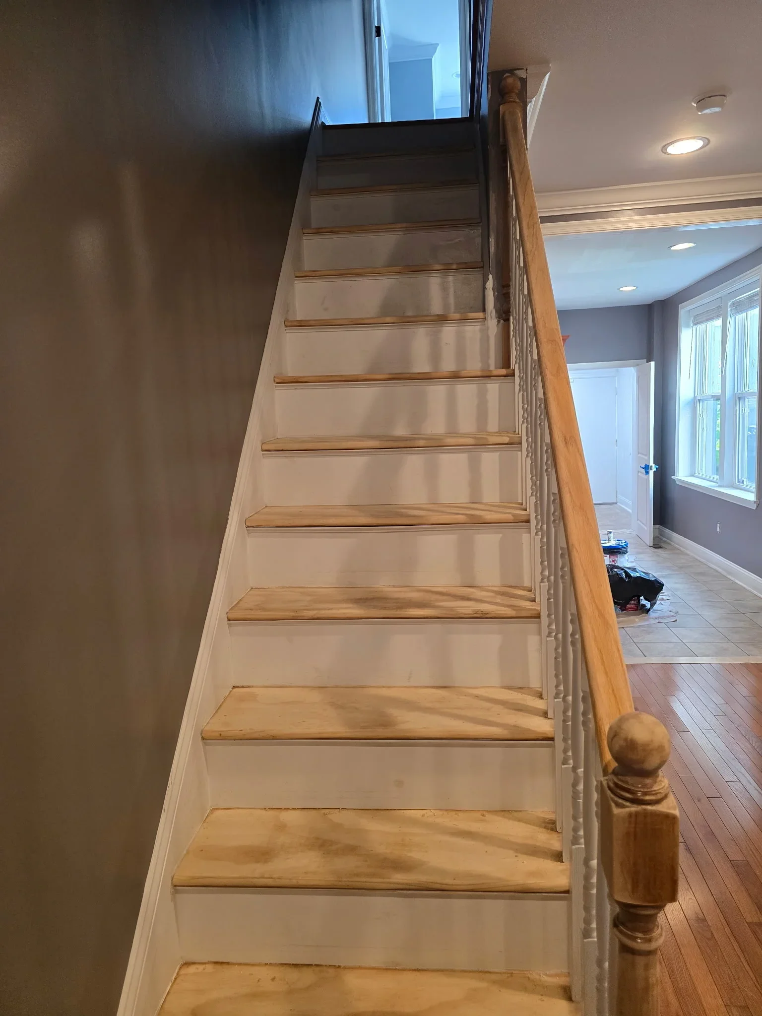Painted interior staircase with white risers, wood treads, wooden handrail, and recessed lighting