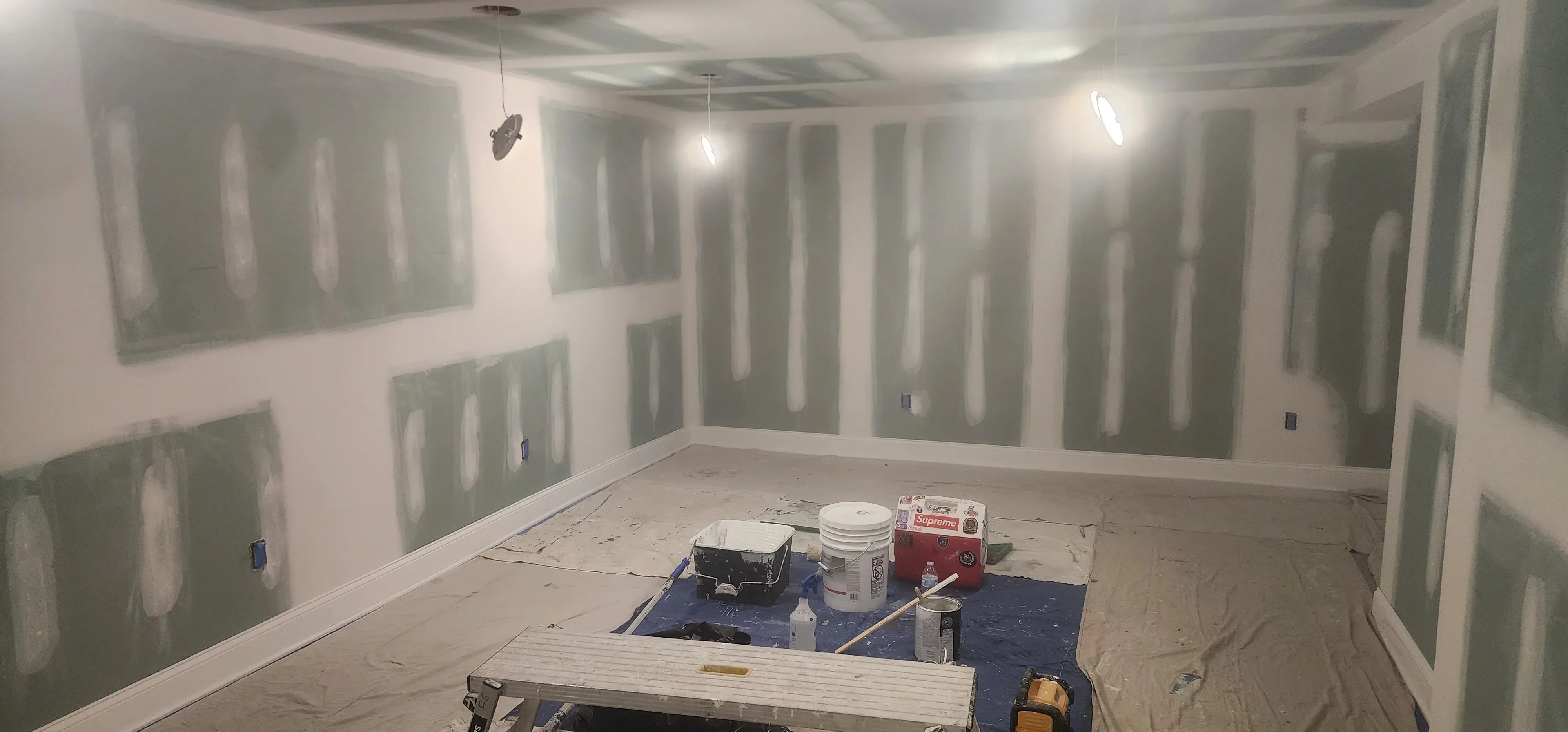 Drywall taping and mudding in progress with primer coating on walls and ceiling