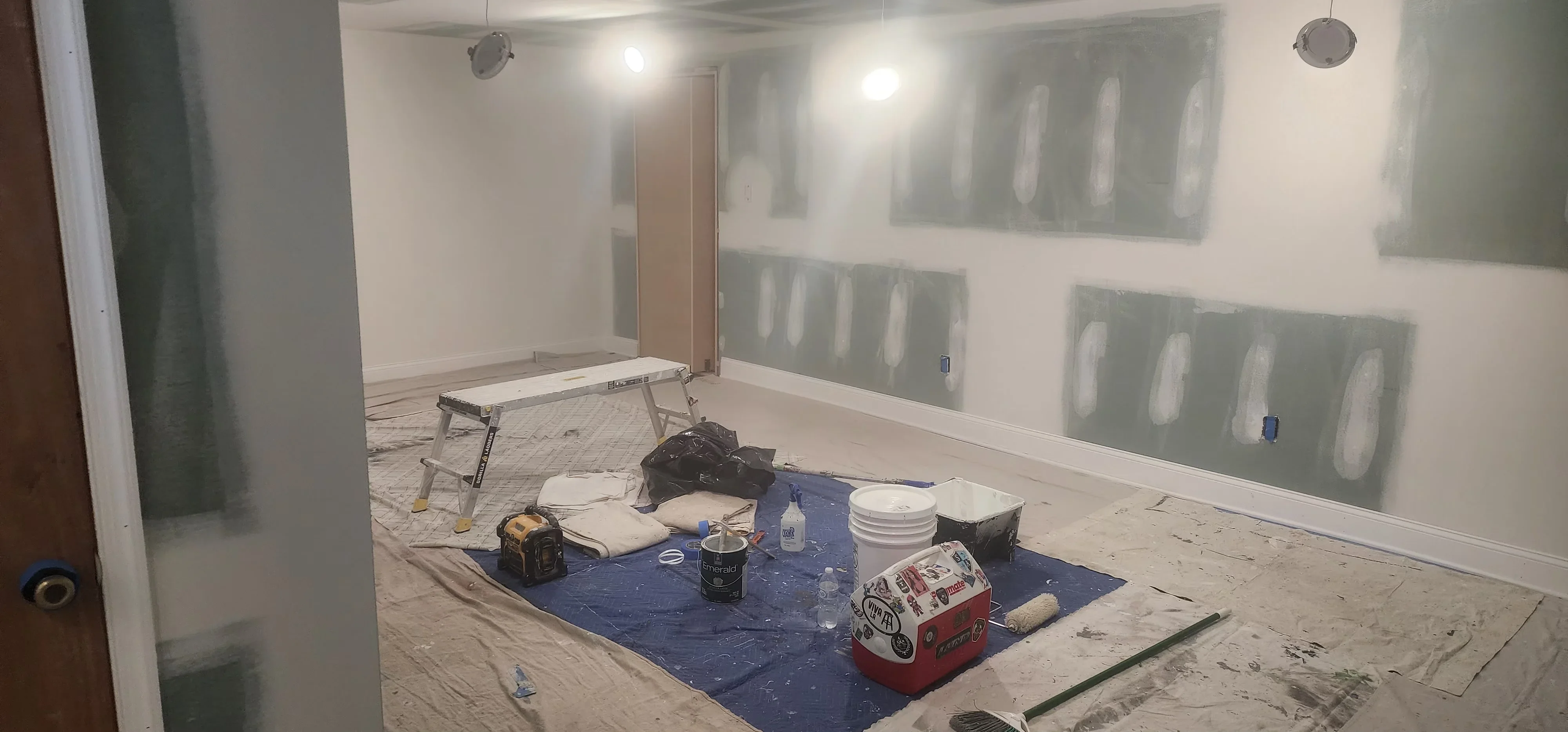 Interior room with drywall installation, joint compound mudding, and paint prep materials