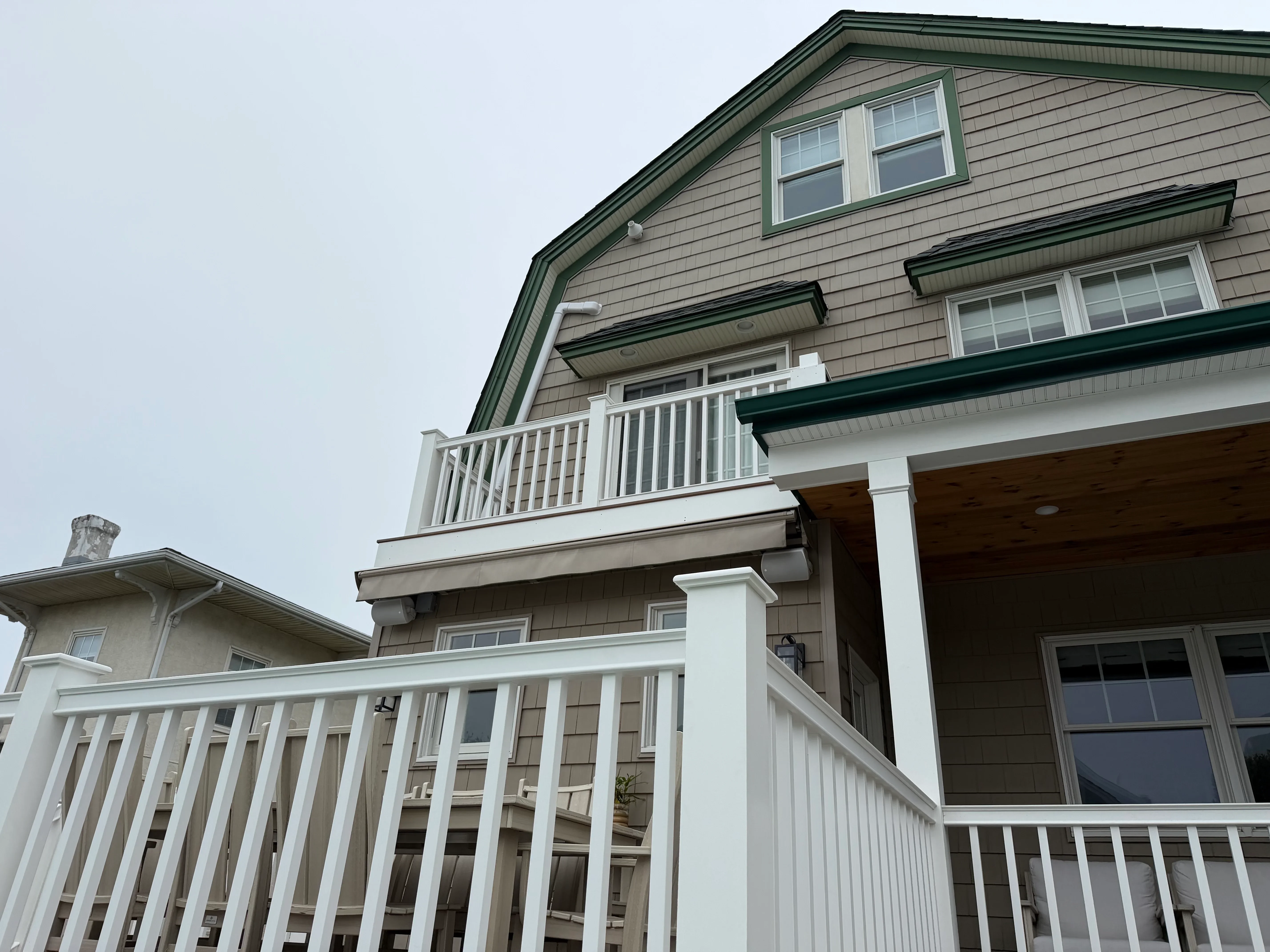 White painted railings and trim on house exterior with taupe siding and green roof accents