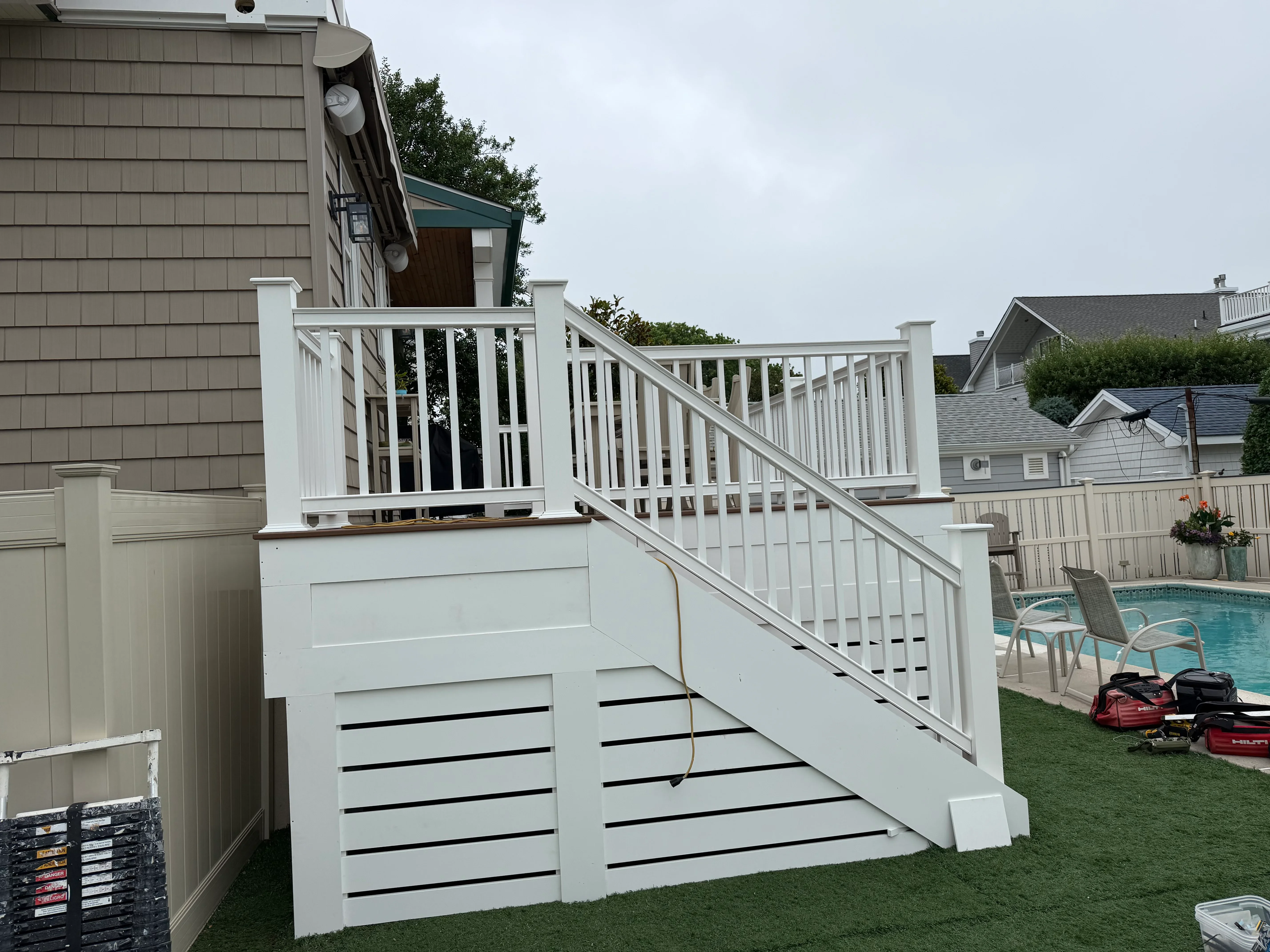 White painted deck with stairs, railings, and black accent straps overlooking pool area