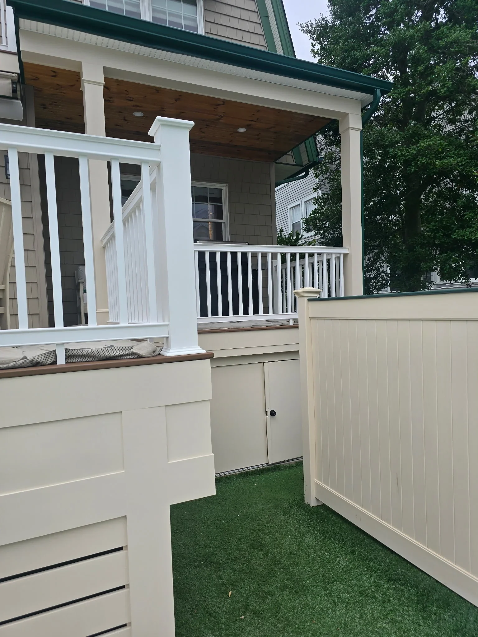 White painted deck railing, trim, and columns on residential porch with wood ceiling