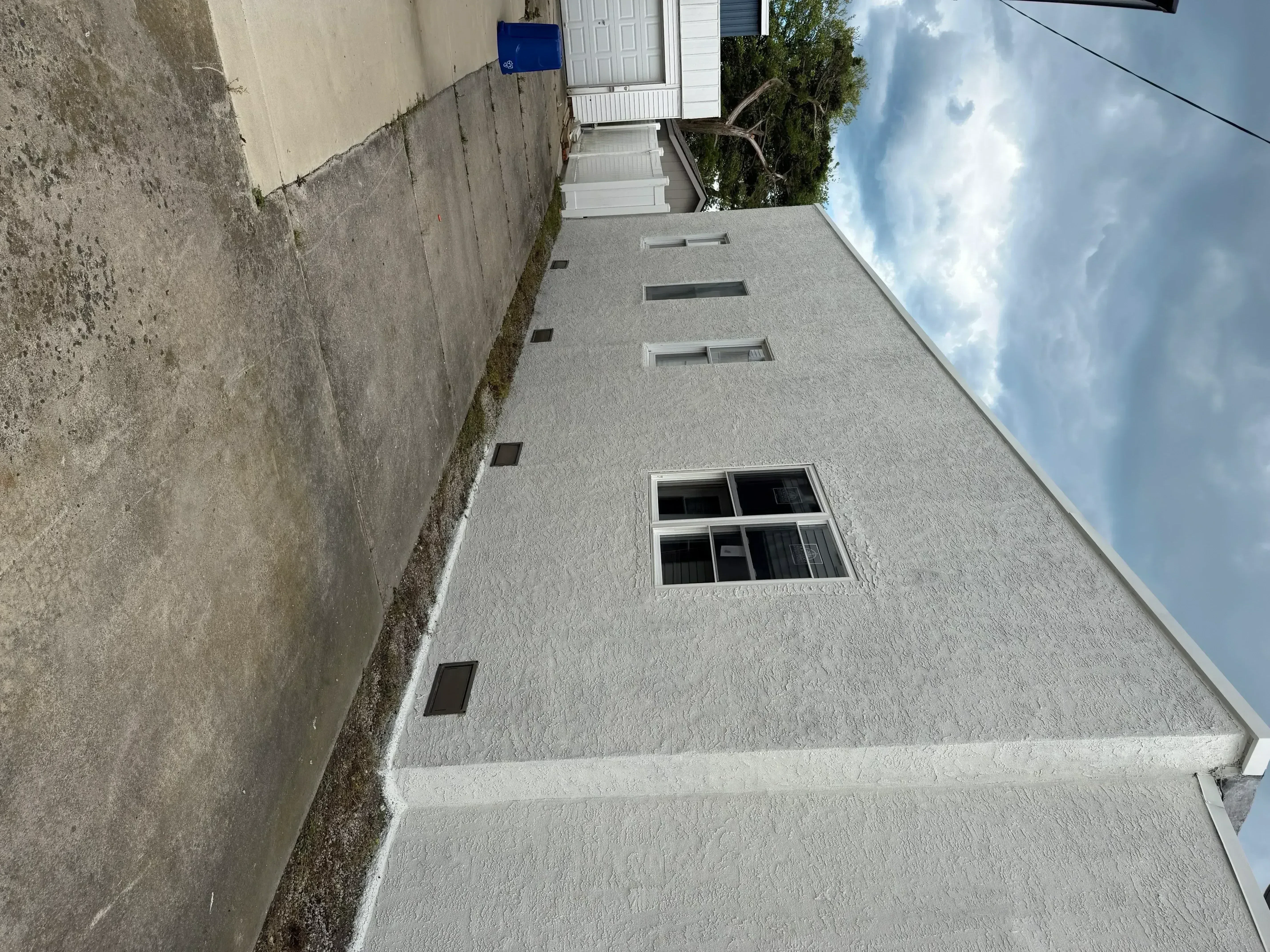 Light gray painted house exterior with windows and vents, professional finish
