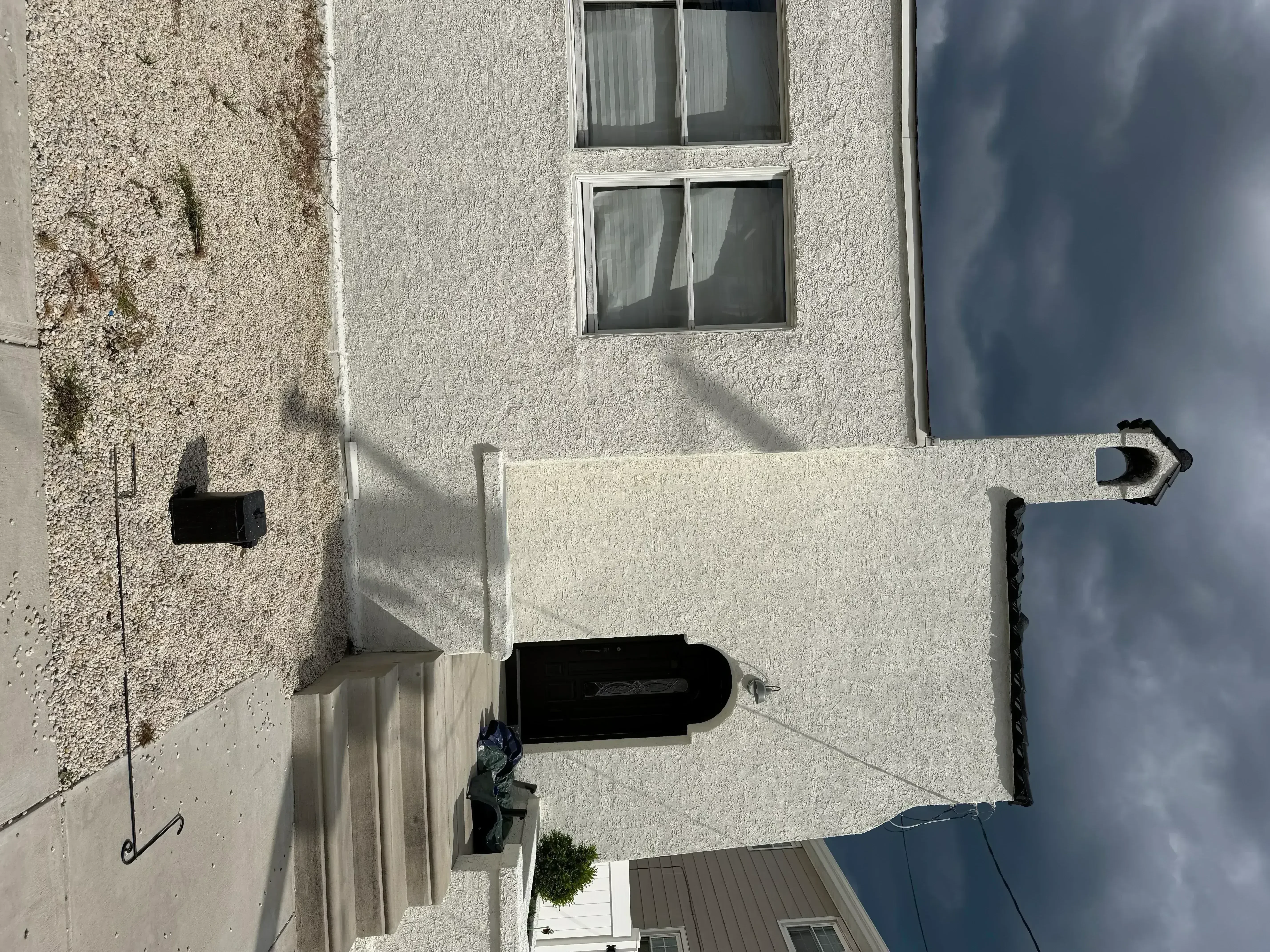 White stucco exterior house with freshly painted walls, windows, and trim work