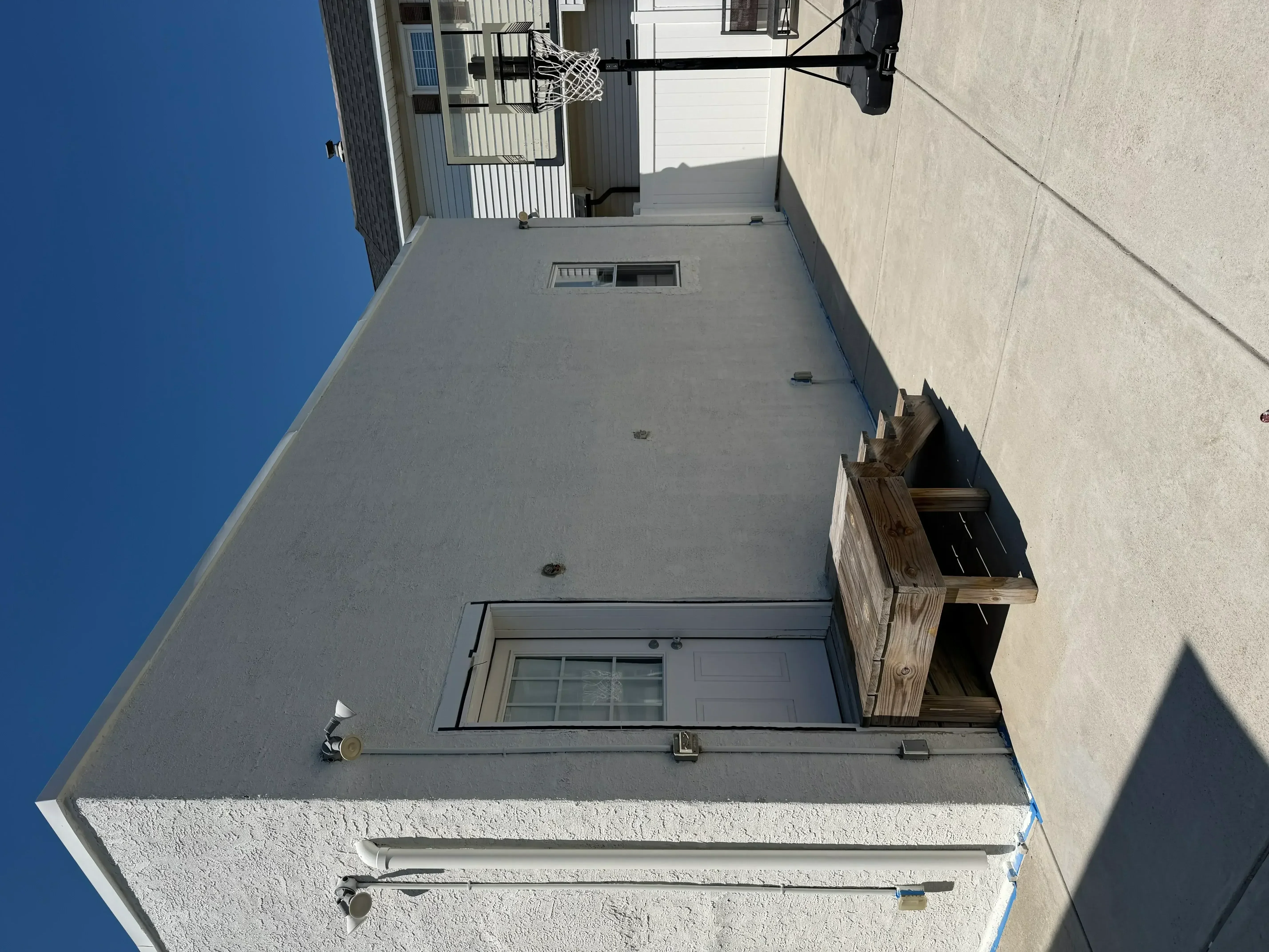 Freshly painted gray flat roof with white stucco walls and metal trim details