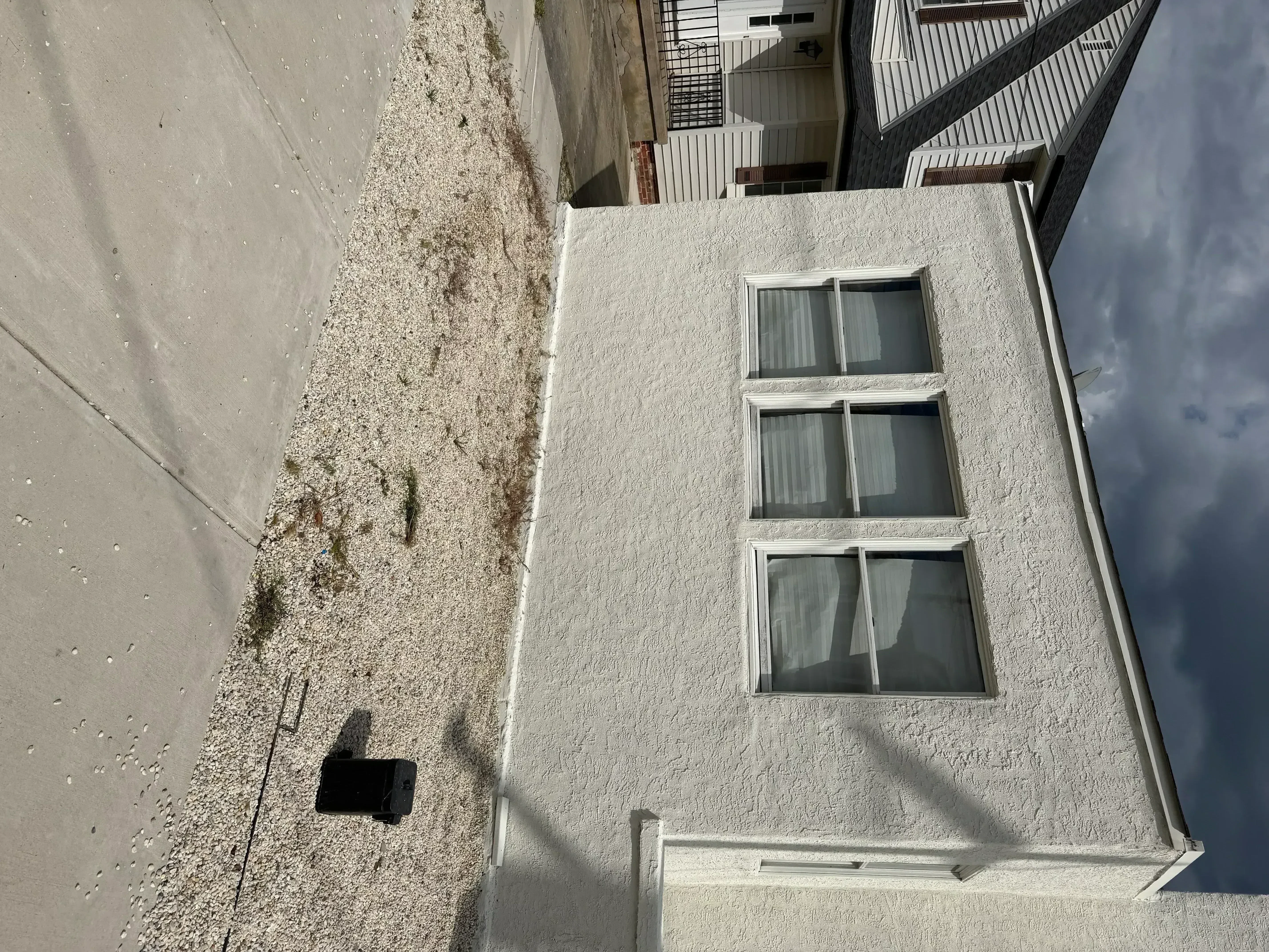 White stucco exterior wall with three windows and painted trim after completion
