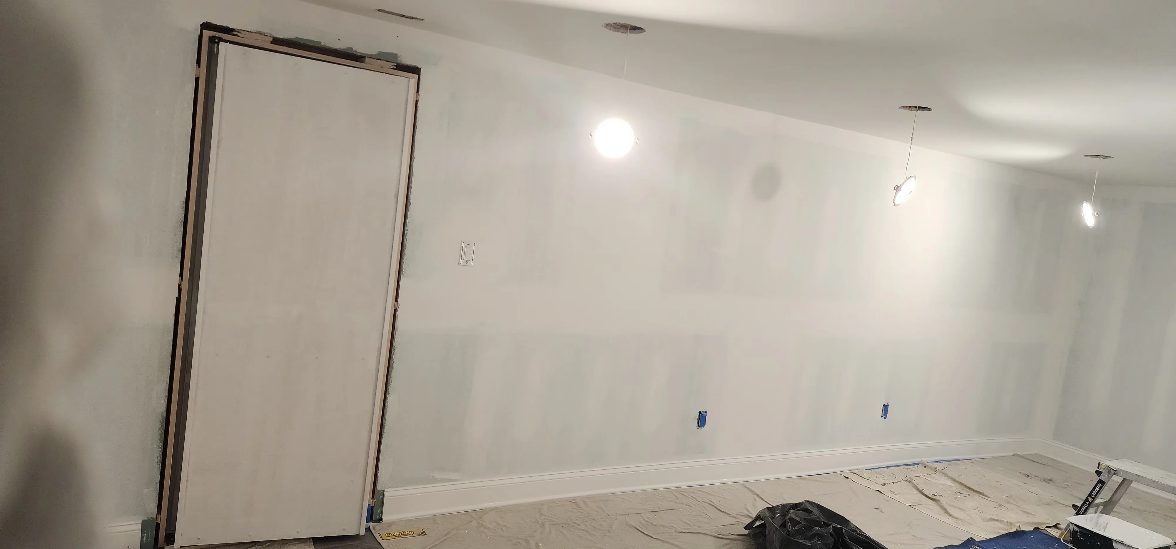 Interior room with finished drywall, primer coat, recessed lighting, and electrical outlets installed