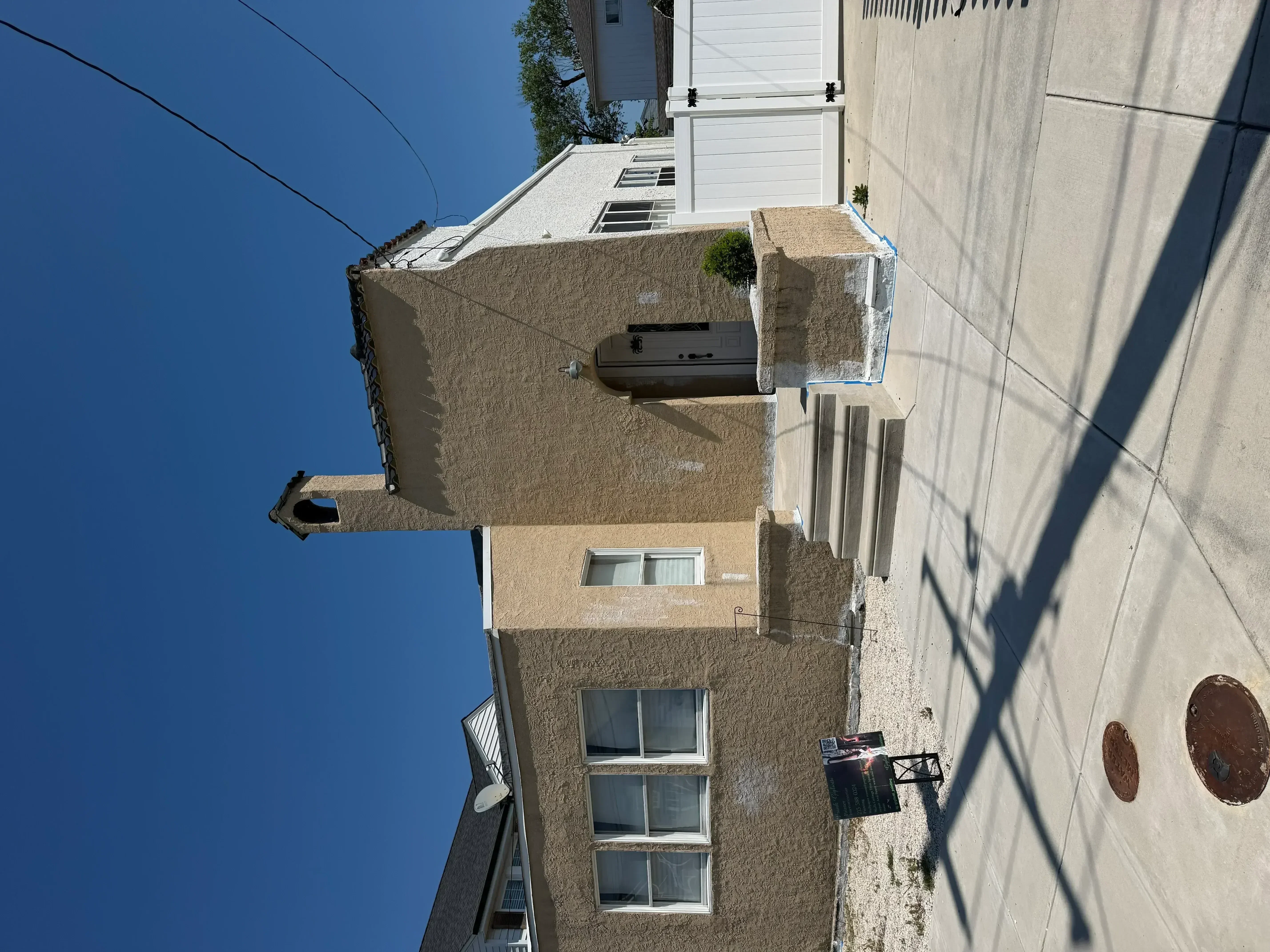 Multi-story stucco house exterior with tan painted walls and white trim windows