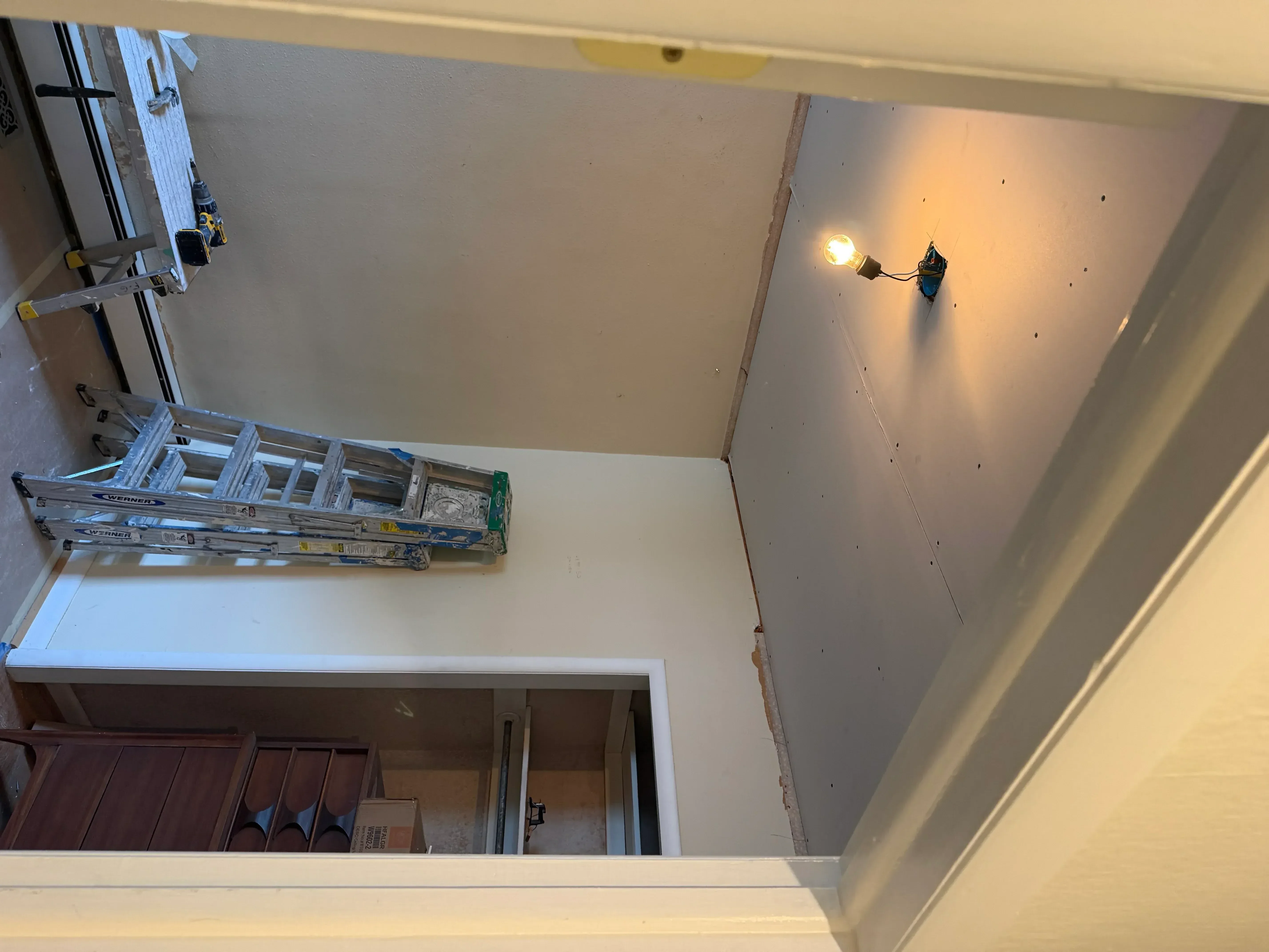Drywall installation with taped seams, mudded joints, and electrical outlet cutouts in residential interior