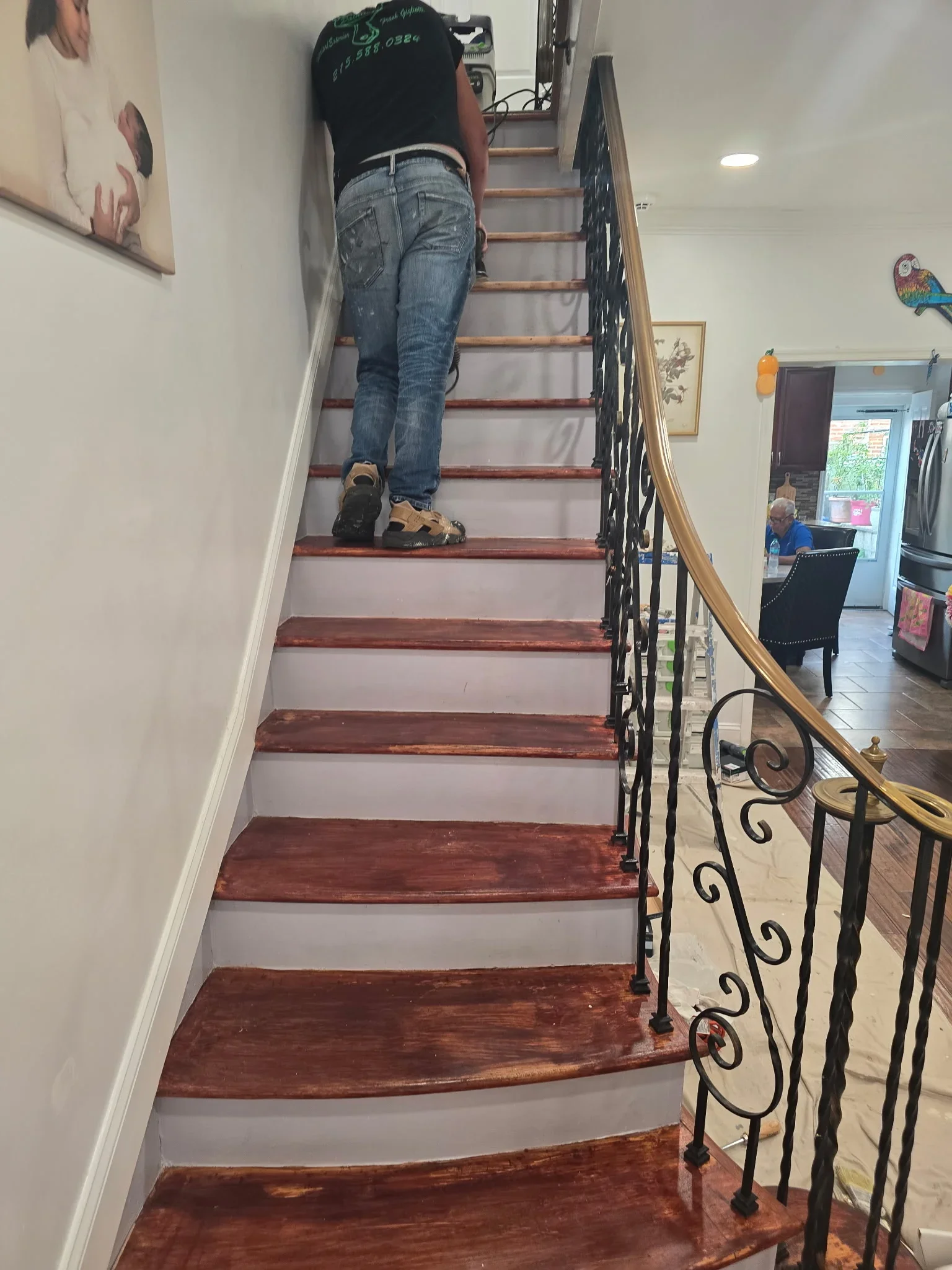 Interior staircase with painted drywall risers and stained wood treads, wrought iron railing