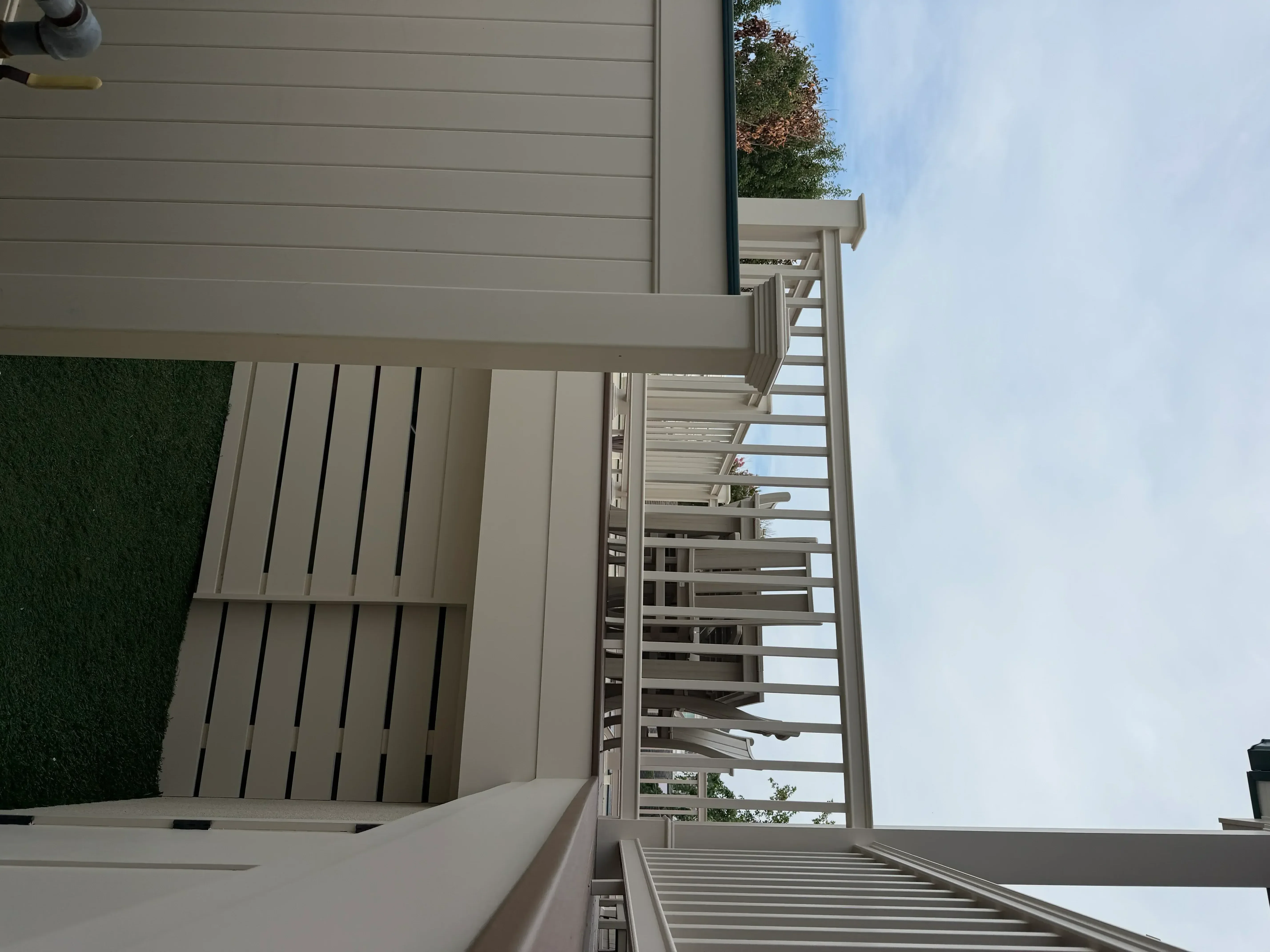 Gray painted horizontal siding, trim, and pergola structure with green accent wall