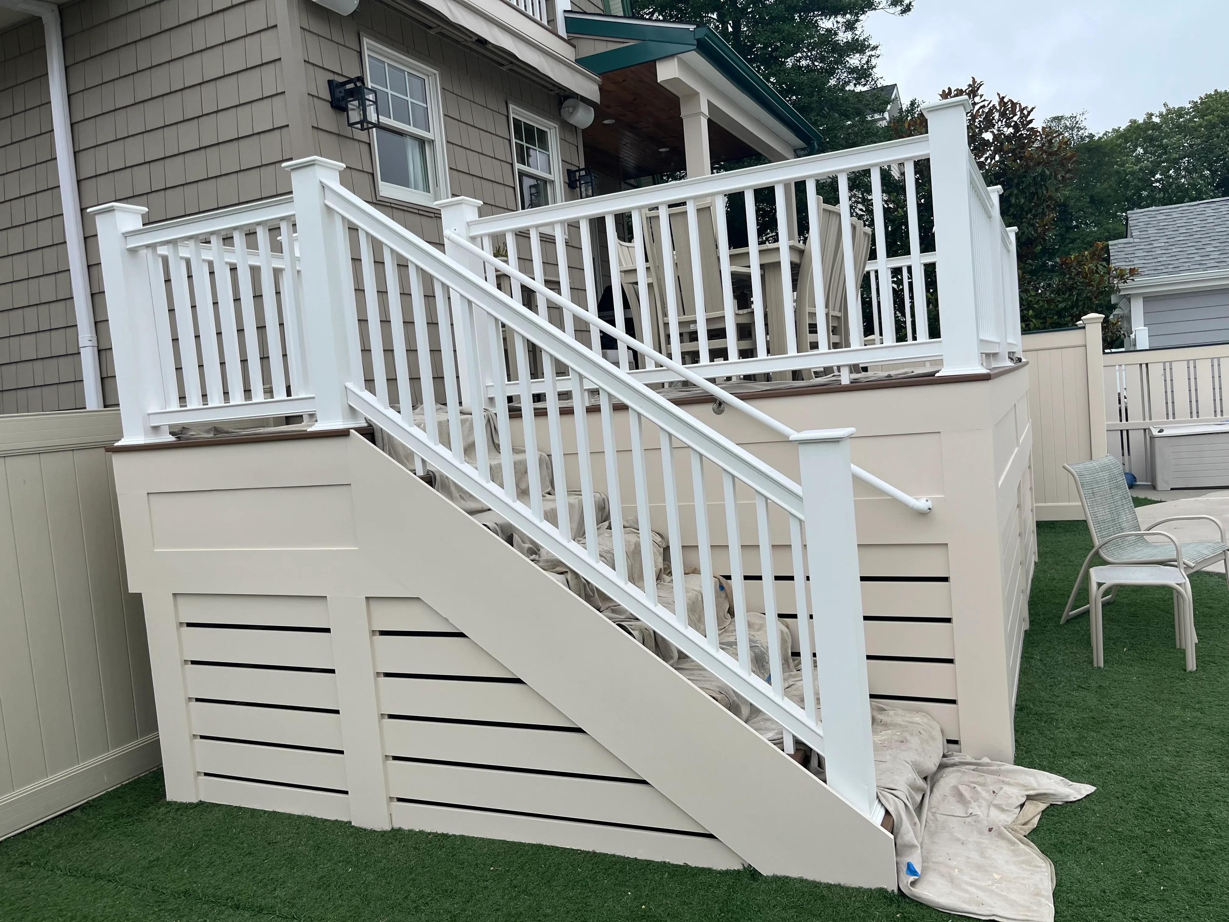 White painted deck railings and cream skirting with black stripe accents on residential deck