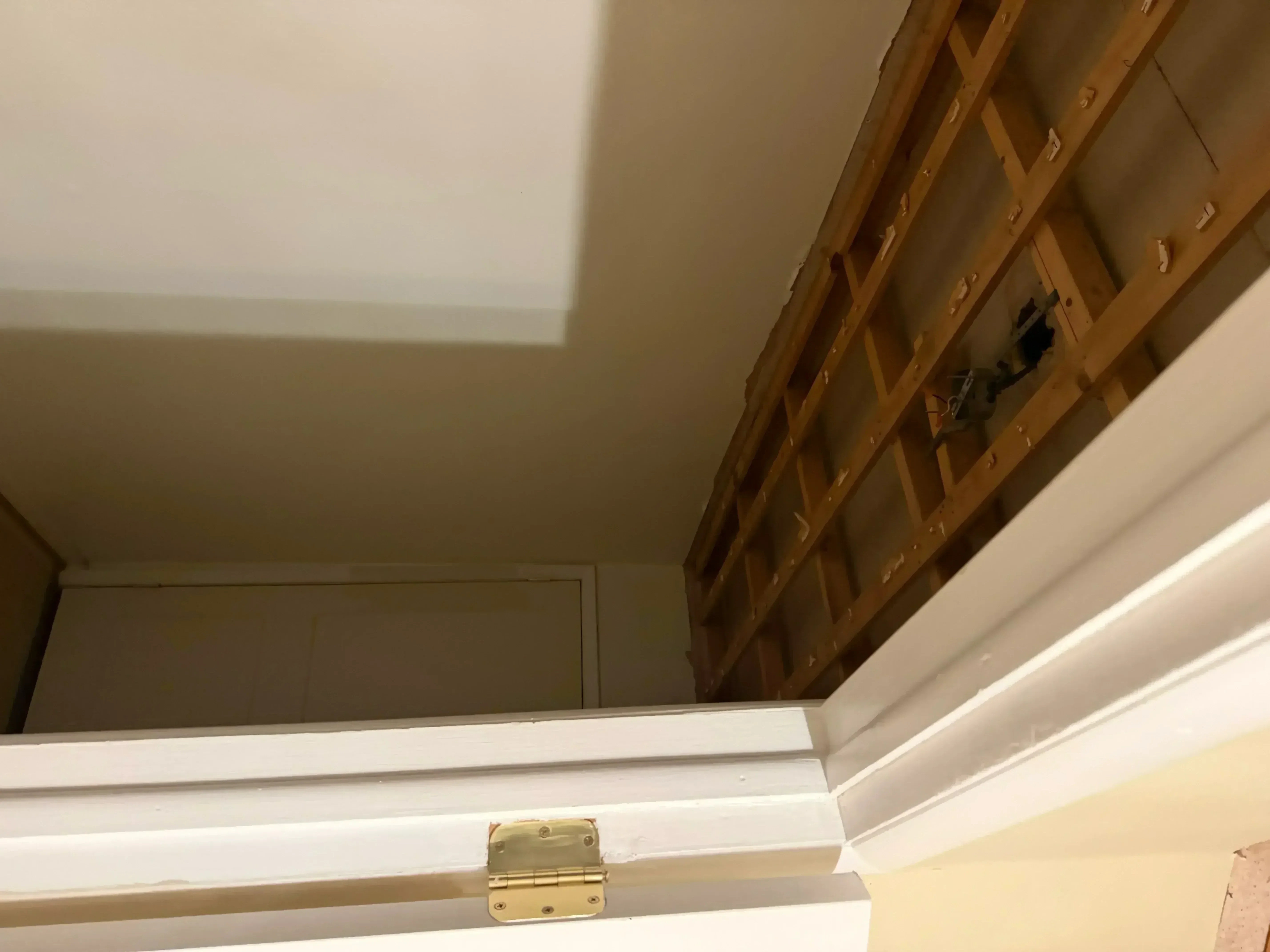 White painted closet interior with wooden shelving, brass hinge hardware, and finished trim work