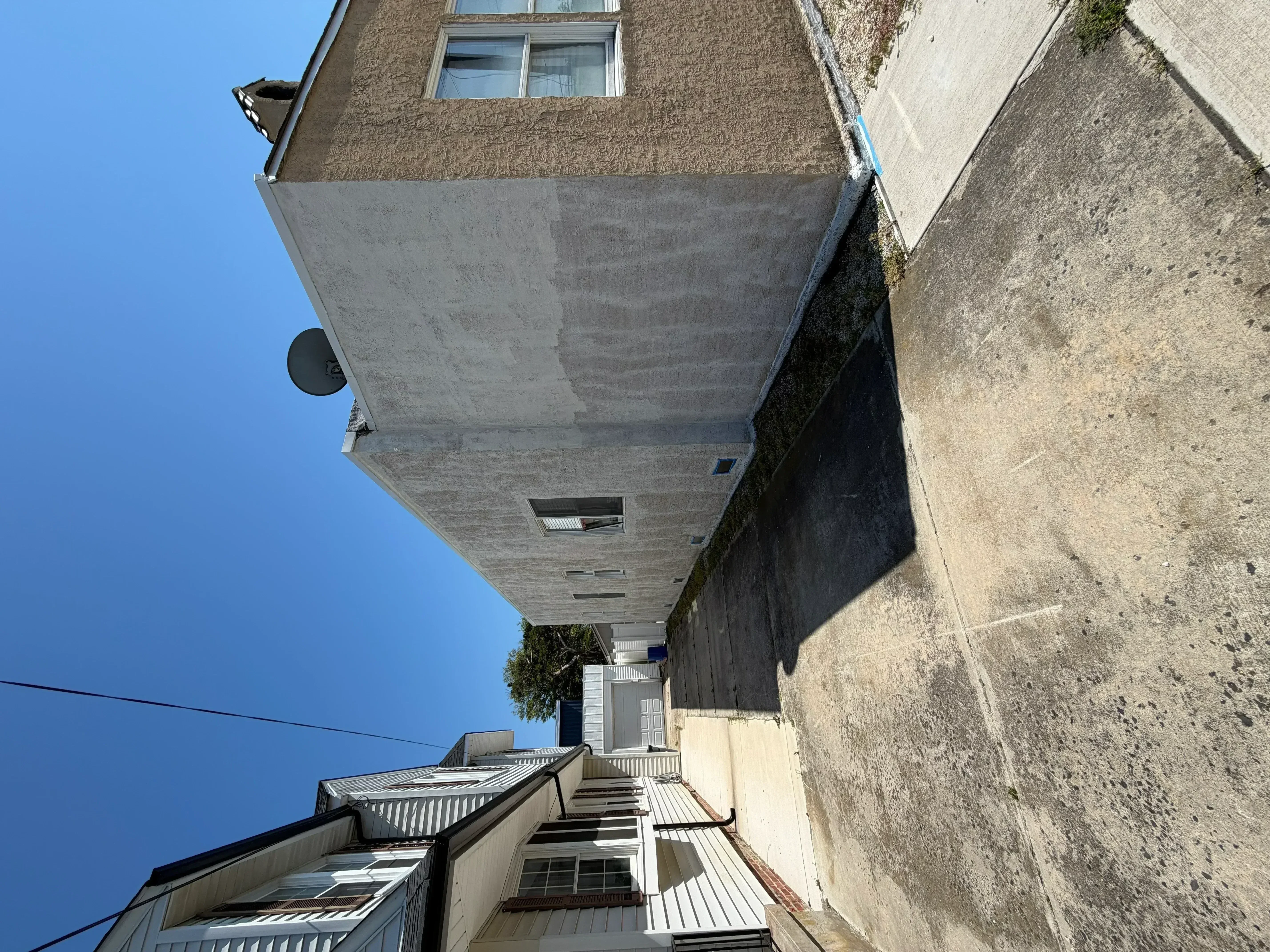 Multi-story building exterior with freshly painted concrete and stucco facade, textured walls, and window trim