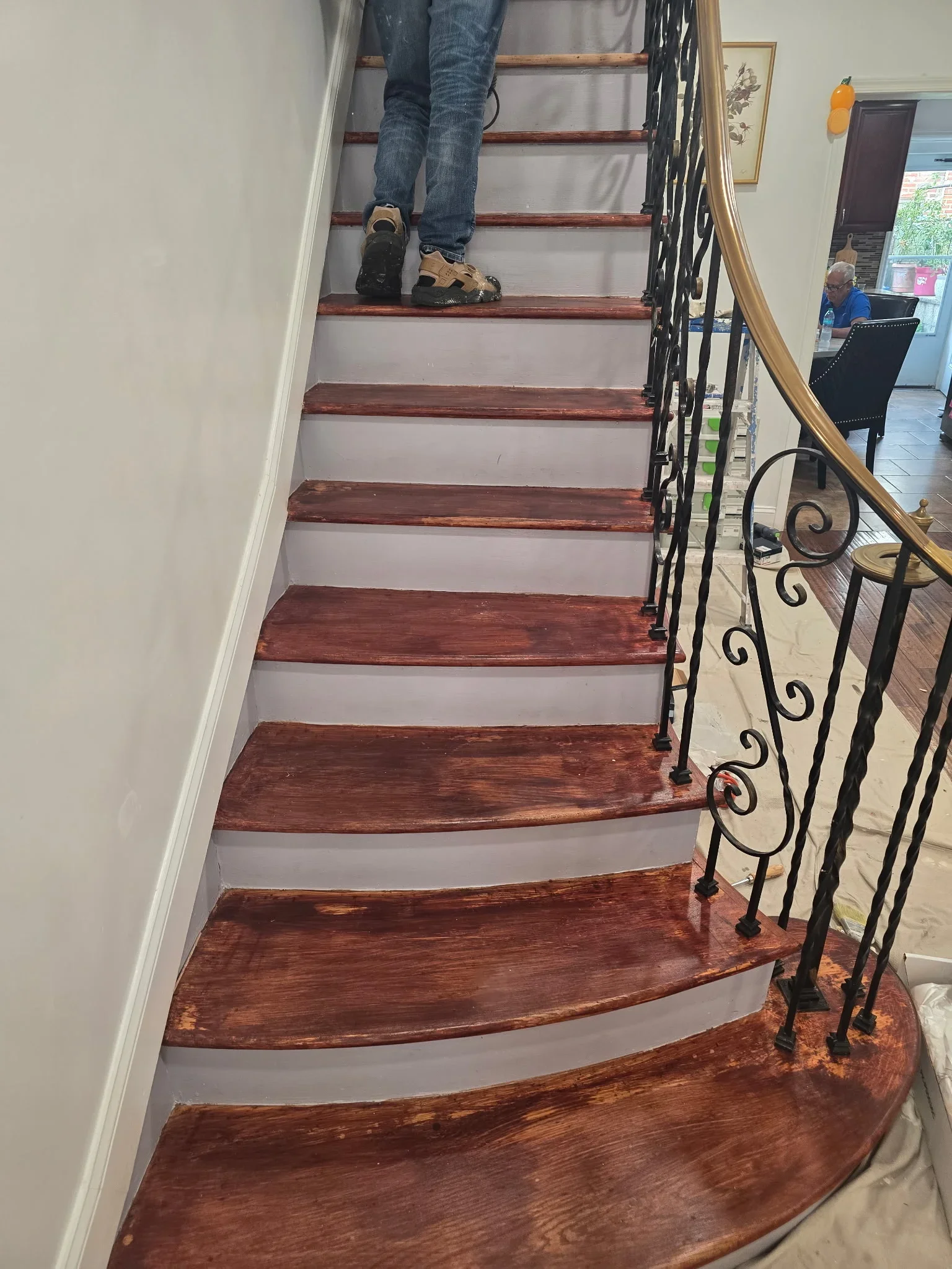 Staircase with stained wood treads and gray-painted drywall risers, wrought iron railing
