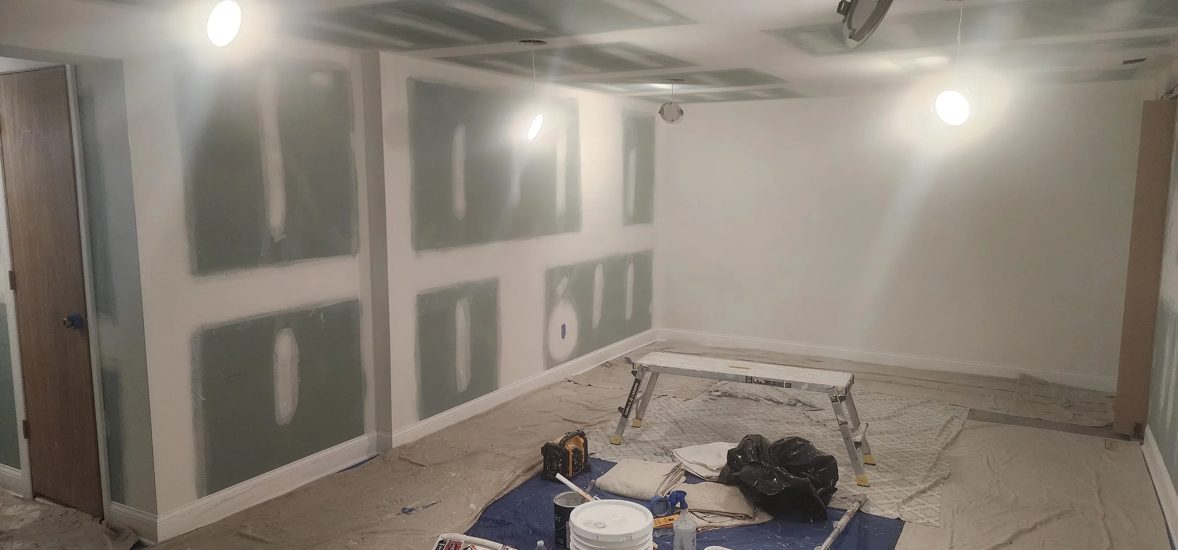 Drywall taping and joint compound application with primer coating on interior walls